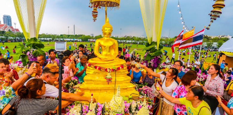 люди поливают статую будды