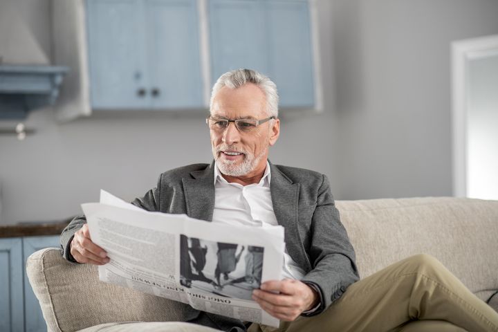 Мужчина предпенсионного возраста читает газету